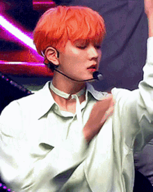 a young man with orange hair is wearing a microphone and a choker around his neck
