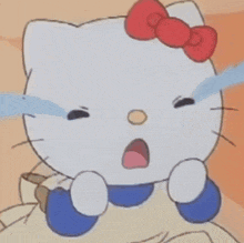 a hello kitty doll is sitting on the floor next to a table .