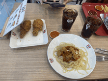 a plate of spaghetti sits on a table next to a plate of fried chicken