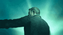 a man in a black jacket is standing in the dark with his arms outstretched