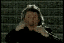 a blurry picture of a man in a black jacket making a funny face