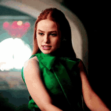 a woman in a green dress is standing in a dark room .