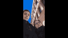 a man and a woman are posing for a picture in front of a building