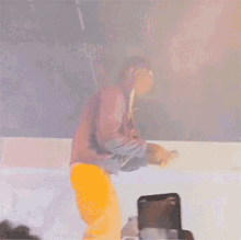 a man in a red jacket and yellow pants is sitting on a white surface
