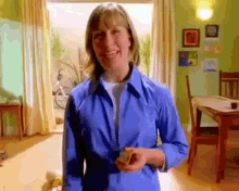 a woman in a blue shirt is smiling in a room