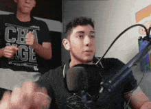 a man is giving a thumbs up while sitting in front of a microphone in a room .