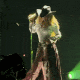 a woman wearing a cowboy hat is singing into a microphone .