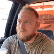 a man with a beard is sitting in a car and looking out the window