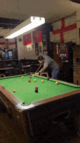 a man is playing pool in a bar with flags on the walls