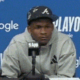a man wearing a hat with the letter a on it is sitting in front of a microphone ..