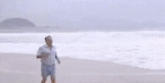 a man in a striped shirt is standing on a beach .