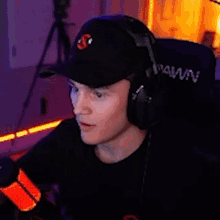 a man wearing headphones and a baseball cap is sitting in a chair .