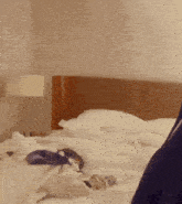 a bed with white sheets and pillows and a lamp