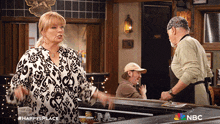 a woman is standing in front of a bar with a nbc logo on the bottom