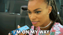 a woman is holding a cell phone in her hand and says i 'm on my way .