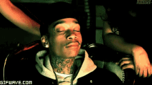 a man with a tattoo on his neck is sitting in a chair with a woman behind him ..