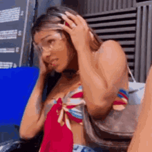 a woman in a bikini is talking on a cell phone while wearing glasses .
