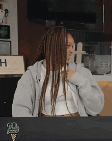 a woman with braids is sitting at a table with a sign that says h on it