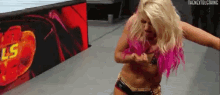 a woman with blonde hair and pink highlights is standing in front of a sign that says ls