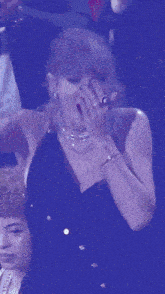 a woman in a black dress is covering her mouth with her hand