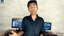 a man standing in front of two computer monitors with a gifs.com watermark on the bottom right