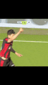 a soccer player wearing a black and red jersey with a bank logo