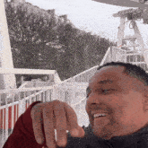a man is smiling and pointing at something in front of a white railing