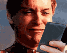 a man in a plaid shirt is crying while looking at a cell phone
