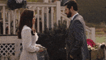 a man in a suit and a woman in a white dress standing next to each other