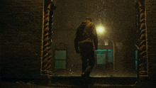 a man walking in the rain with a light behind him