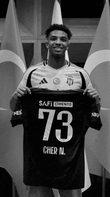 a black and white photo of a man holding a jersey with the number 73 on it