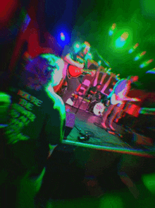 a blurry picture of a band on stage with a drummer wearing a shirt that says ' slayer ' on the back