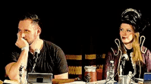 a man and a woman are sitting at a table with bottles of water in front of them
