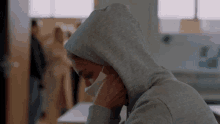 a person wearing a hooded sweatshirt and a mask on their face .