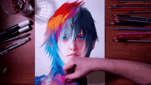 a drawing of a person with colorful hair is on a table surrounded by colored pencils