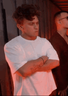 a man in a white t-shirt has a tattoo on his arm