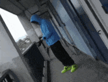 a person wearing a blue hoodie and neon green nike shoes
