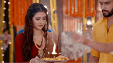 a woman is holding a plate of food and a man is holding a lamp .