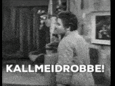 a black and white photo of a man standing in a room with the words `` kallmeidrobbe '' .