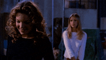two women are standing next to each other and one is smiling