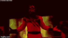 a man in a red costume with his arms outstretched in a dark room .
