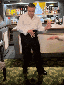 a man in a white shirt and black pants is dancing in a bar