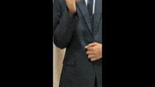a man in a suit and tie is clapping his hands in front of a wall .