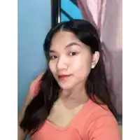a young woman wearing a pink shirt and white earrings