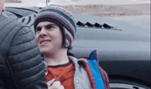 a man wearing a knitted hat is talking to a man in a leather jacket