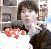 a man is eating a cake with strawberries on it