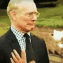 a man in a suit and tie is being touched by a woman 's hand .