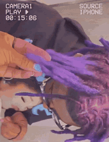 a person with purple dreadlocks is being filmed by a camera that says source iphone