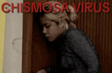 a woman is standing in front of a door with the words chismosa virus written on the wall behind her .