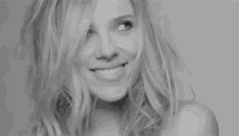 a black and white photo of a woman with long blonde hair making a face .